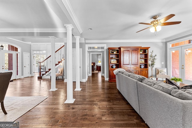 living room with french doors, decorative columns, dark wood-type flooring, ornamental molding, and stairs