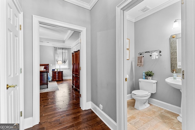 bathroom featuring toilet, baseboards, visible vents, and ornamental molding