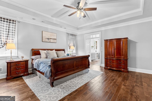 bedroom with dark wood-style floors, baseboards, a raised ceiling, and crown molding