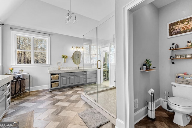 bathroom with baseboards, toilet, lofted ceiling, vanity, and a shower stall