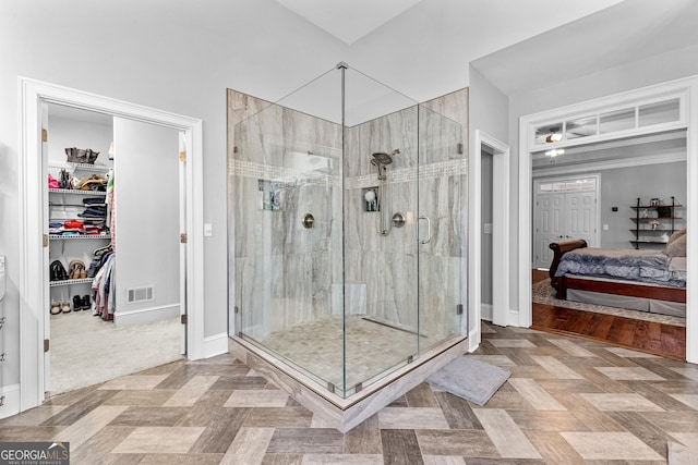 ensuite bathroom featuring visible vents, baseboards, connected bathroom, a walk in closet, and a shower stall