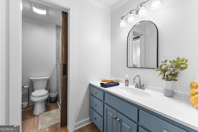 bathroom with toilet, wood finished floors, crown molding, and vanity