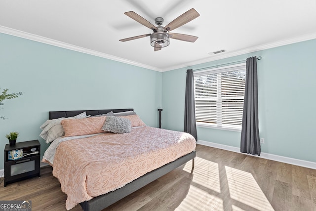 bedroom featuring ornamental molding, wood finished floors, visible vents, and baseboards