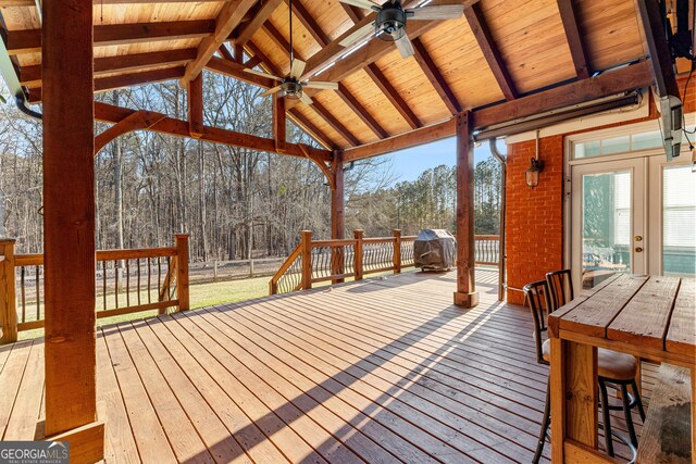 deck with ceiling fan and a forest view