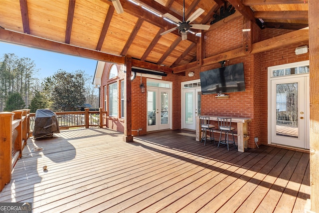 deck with outdoor dry bar, french doors, and a ceiling fan