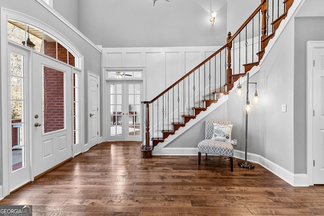 entrance foyer featuring french doors, hardwood / wood-style flooring, a decorative wall, a high ceiling, and stairs