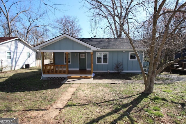 view of front facade with covered porch, a shingled roof, board and batten siding, and a front yard
