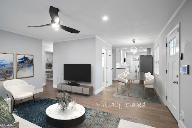 living room with visible vents, ornamental molding, a ceiling fan, wood finished floors, and baseboards