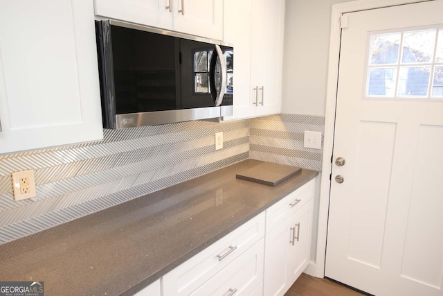 kitchen with white cabinetry, dark stone counters, and backsplash