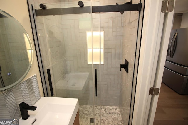 full bath with a stall shower, vanity, and wood finished floors