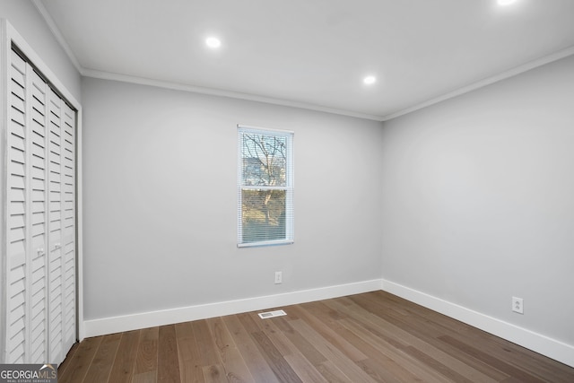 unfurnished bedroom with recessed lighting, wood finished floors, baseboards, a closet, and crown molding