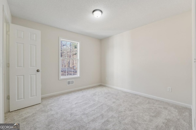 unfurnished room featuring light carpet, a textured ceiling, visible vents, and baseboards