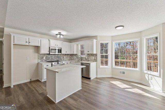 kitchen with stainless steel appliances, light countertops, a center island, and white cabinets