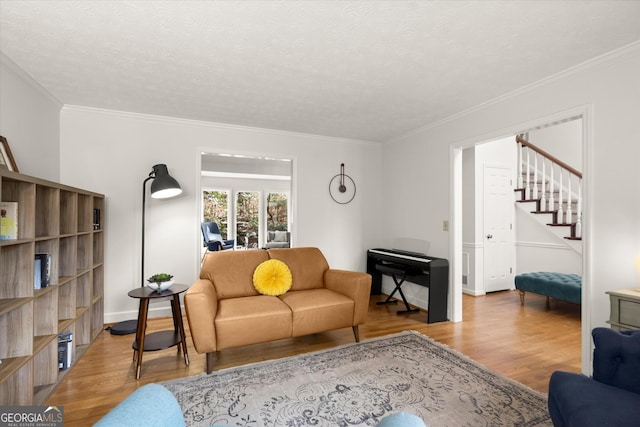 living area with a textured ceiling, ornamental molding, and wood finished floors