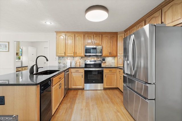 kitchen featuring decorative backsplash, appliances with stainless steel finishes, a sink, dark stone countertops, and a peninsula