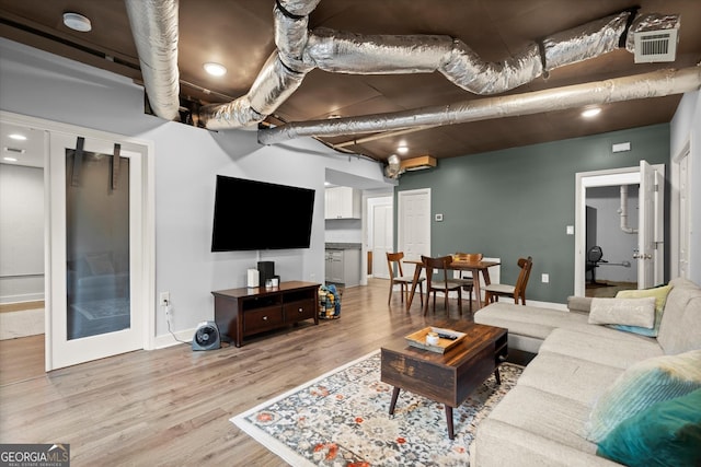 living area featuring baseboards, visible vents, and wood finished floors