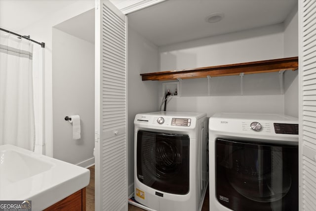 clothes washing area with laundry area, a sink, and separate washer and dryer