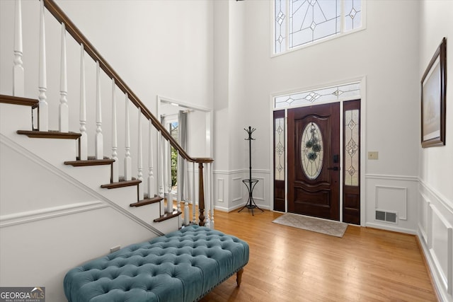 entrance foyer featuring a wainscoted wall, visible vents, a decorative wall, and wood finished floors