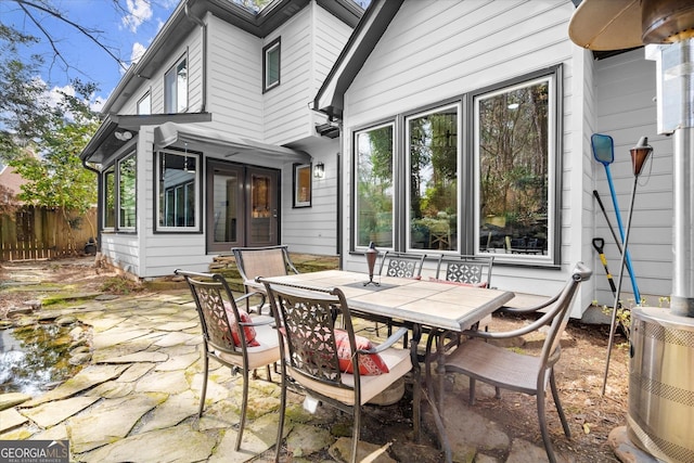 view of patio featuring a sunroom, fence, outdoor dining area, and cooling unit