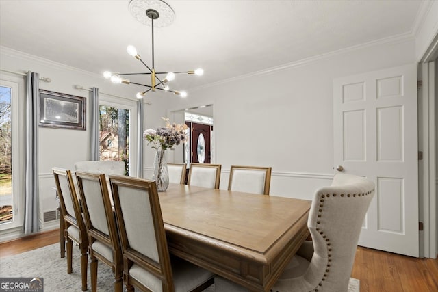 dining room featuring a notable chandelier, ornamental molding, and light wood-style floors