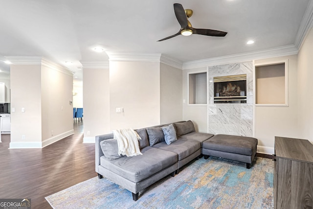 living area featuring baseboards, ceiling fan, wood finished floors, and crown molding