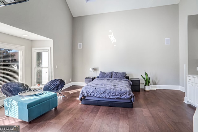 bedroom with dark wood-style floors, vaulted ceiling, and baseboards