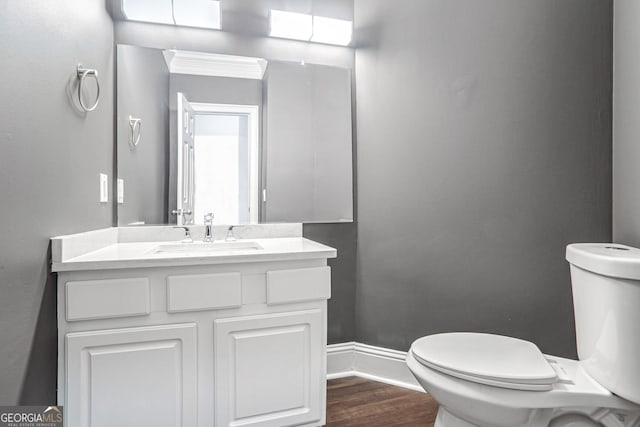 bathroom featuring toilet, baseboards, wood finished floors, and vanity