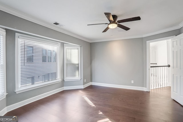 spare room with baseboards, visible vents, dark wood finished floors, and crown molding