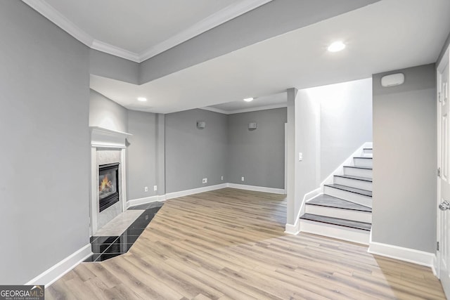 living room featuring light wood-style flooring, a fireplace, baseboards, stairs, and ornamental molding