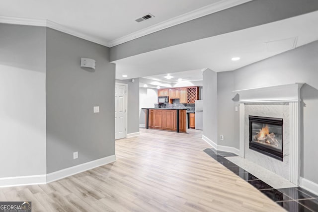 unfurnished living room featuring ornamental molding, visible vents, light wood-style floors, and baseboards