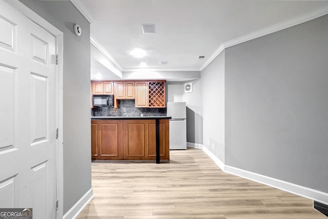 kitchen with black microwave, freestanding refrigerator, brown cabinets, tasteful backsplash, and dark countertops