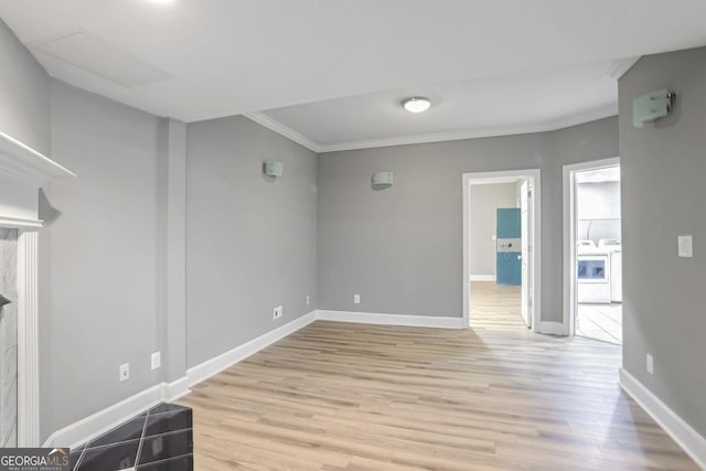 spare room featuring light wood-style flooring, washer / clothes dryer, baseboards, and ornamental molding