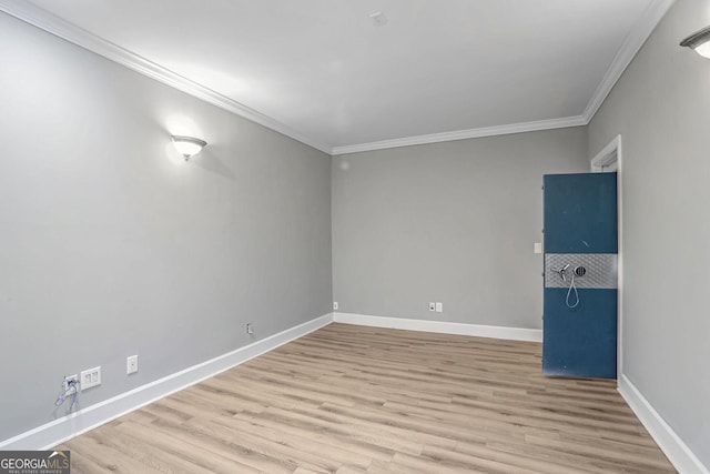 spare room featuring light wood-style floors, crown molding, and baseboards