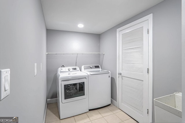 clothes washing area with washing machine and dryer, laundry area, baseboards, and light tile patterned floors