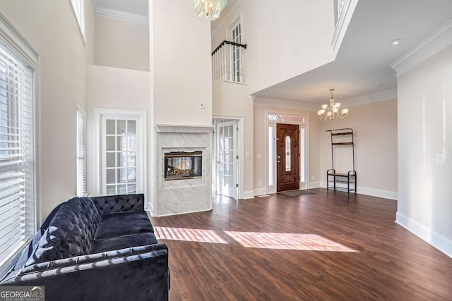 living area featuring crown molding, dark wood-type flooring, baseboards, and an inviting chandelier