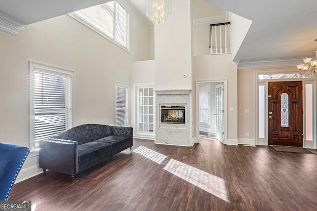 living room featuring ornamental molding, dark wood finished floors, a notable chandelier, and baseboards