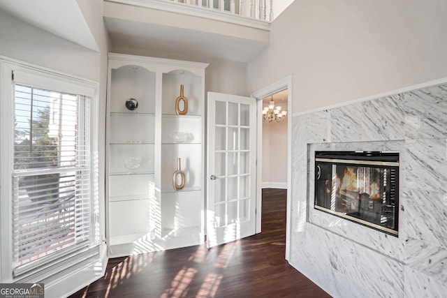 interior space with dark wood-style floors, a fireplace, and an inviting chandelier