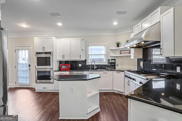 kitchen with double oven, range hood, white cabinetry, and open shelves