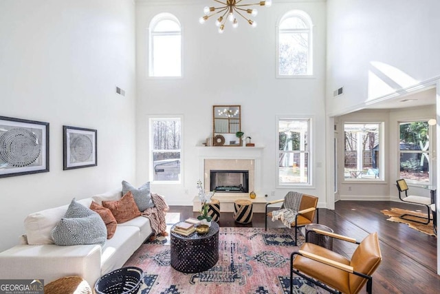 living room with dark wood-style flooring, a premium fireplace, visible vents, and baseboards