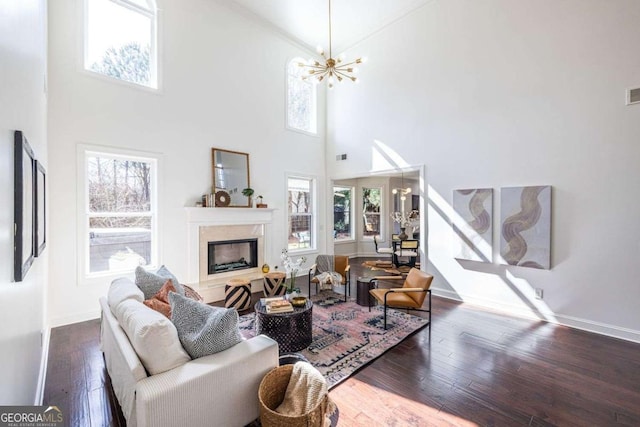 living room featuring dark wood-style floors, a chandelier, a fireplace, and baseboards