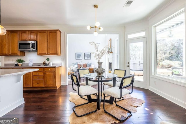 interior space with visible vents, dark wood-style flooring, a wealth of natural light, and ornamental molding