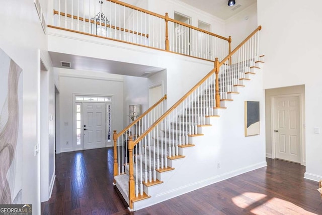 foyer with a high ceiling, dark wood finished floors, visible vents, and baseboards