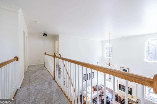 hallway featuring crown molding, light colored carpet, an inviting chandelier, an upstairs landing, and baseboards