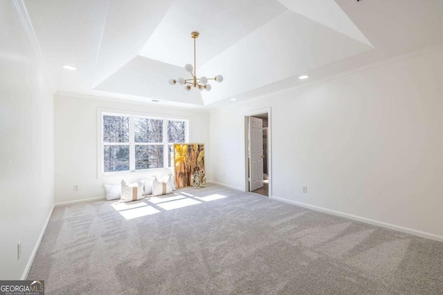 empty room featuring ornamental molding, a tray ceiling, baseboards, and carpet