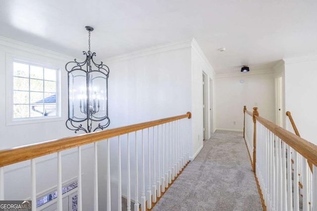 hallway with a chandelier, ornamental molding, light carpet, and baseboards