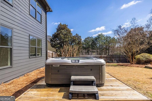 wooden deck with a hot tub and fence