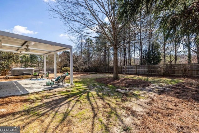 view of yard featuring a hot tub, ceiling fan, a fenced backyard, and a patio