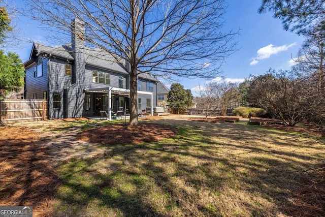 rear view of property with a lawn and fence