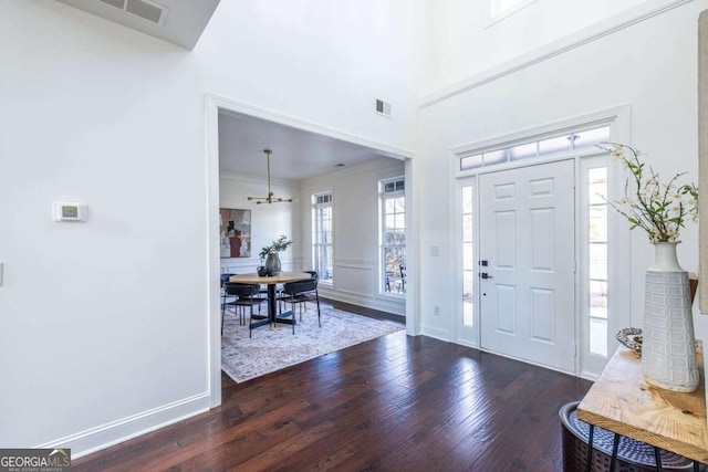 entrance foyer featuring ornamental molding, dark wood-style flooring, visible vents, and baseboards