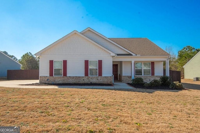 view of front of property with a front lawn, cooling unit, fence, and brick siding